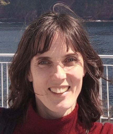 Me smiling, out of doors. I've got dark wavy hair and a red top.