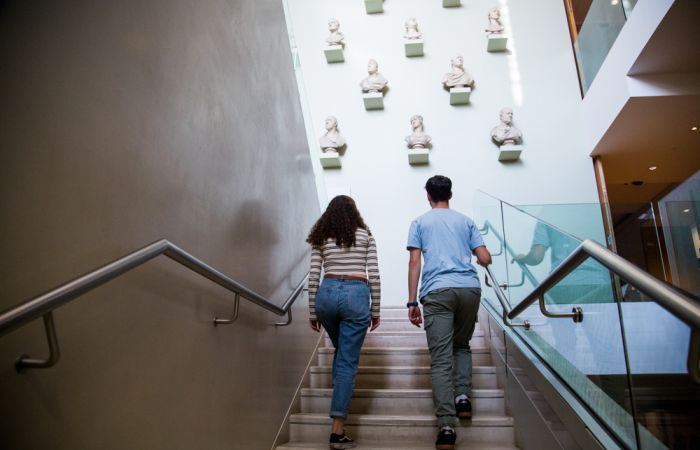 Two people climbing stairs in Ashmoleum Museum viewing an exhibition