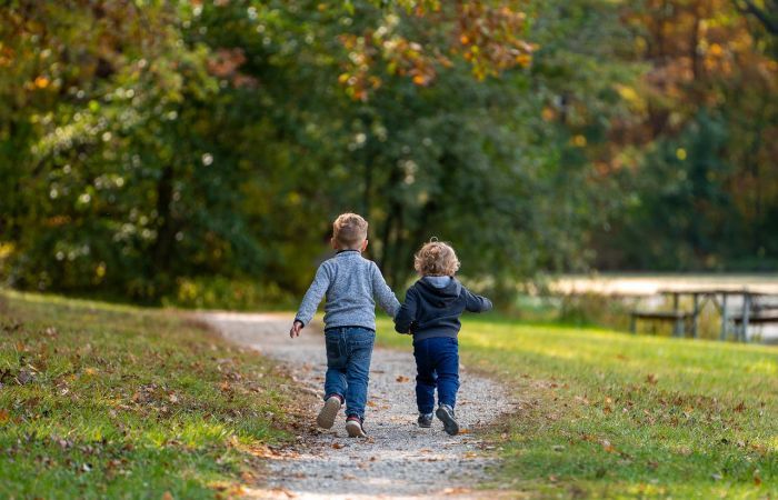 A photo of children running into the distance down a footpath outdoors, holding hands
