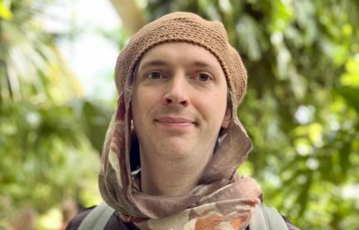 Headshot of Dr Peaks wearing a head scarf and beret against out-of-focus trees in the background