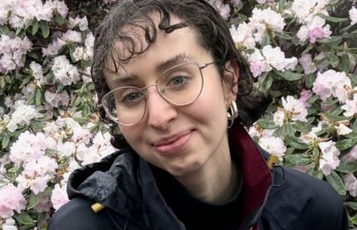 Person smiling in front of flowers