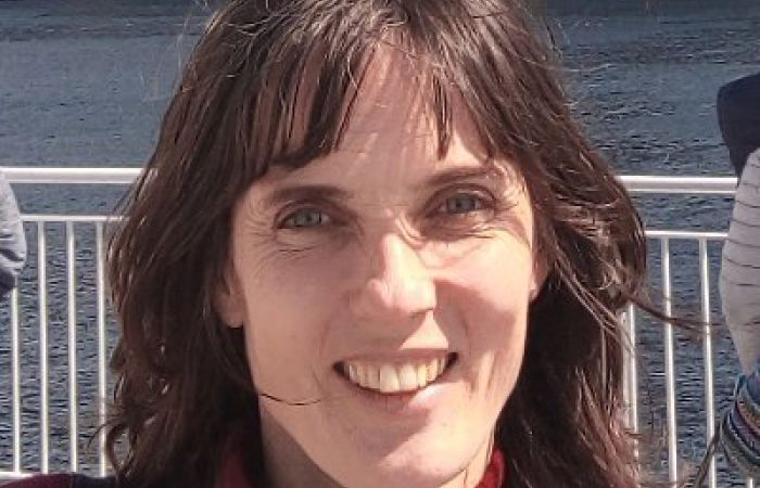 Me smiling, out of doors. I've got dark wavy hair and a red top.