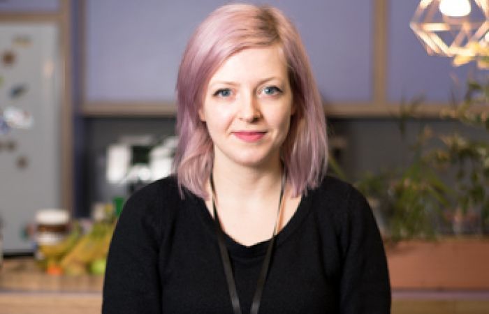 image of Sophie with purple hair wearing a black jumper and a purple background